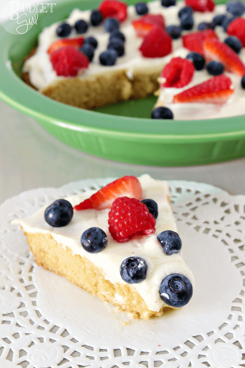 A tender sugar cookie cake, filled with white chocolate chips, topped with cream cheese and fruit. A perfect dessert for the Fourth of July and other summer holiday parties. 